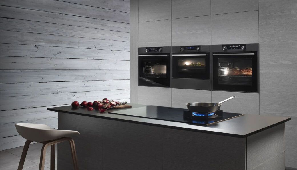 Cucina con tre forni da incasso in colonna e piano a induzione sull'isola